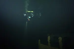 Diver in the dark over a shipwreck covered with mussels