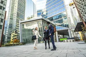 Framed Print : Diverse business professionals having a conversation while walking together through a modern urban financial district