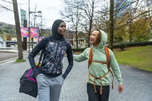 Diverse young adult friends wearing activewear walking and talking in an urban park