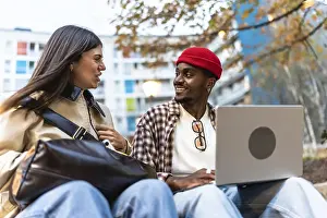Diverse young students sitting outdoors in an urban environment