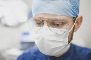 Doctor with glasses and a surgical mask focused on work