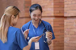Two doctors in blue scrubs engage in a cheerful conversation during their break