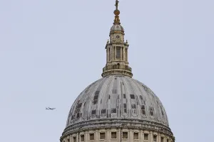 Dome of St. Pauls cathedral with a jet aircraft in the sky behind