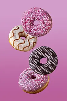 Donuts in chocolate and in sugar glaze fly on a pink background