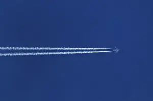 Double contrails behind airplane in the blue sky