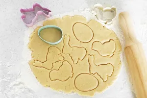 Dough with cookie cutters and rolling pin on kitchen table