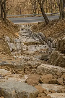 Category Mountain Landscapes Prints: Drainage ditch constructed of large boulders on side of mountain on early spring afternoon in South Korea