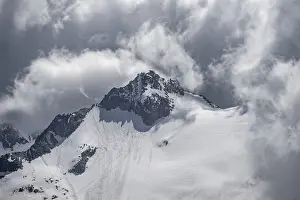 Dramatic clouds, rocky mountain peak with snow and glacier Waxeggkees