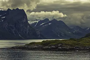 Dramatic mountain silhouette under dark clouds with a calm lake