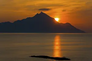 Dramatic sunrise over the mountains with golden reflections on the sea