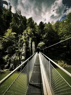 Dramatic view of a suspension bridge over a gorge with rocks