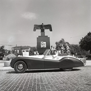 Driving in the 1950s. A young woman in an open convertible Jaguar XK120