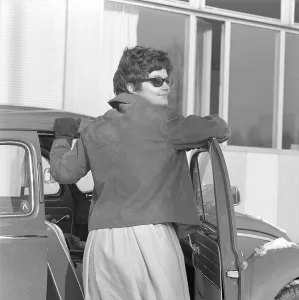 Driving in the 1960s. A woman at her car a Volkswagen Beetle. She is wearing a skirt, a short leather jacket, sunglasses and gloves. Sweden 1962