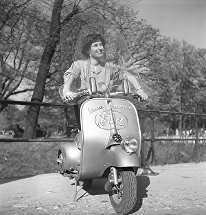 Driving in Italy in the 1950s. A young woman on a Vespa scooter in Milan Italy 1950