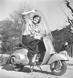 Driving in Italy in the 1950s. A young woman on a Vespa scooter in Milan Italy 1950