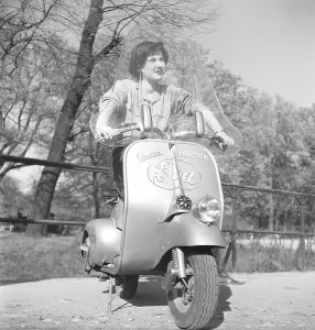 Driving in Italy in the 1950s. A young woman on a Vespa scooter in Milan Italy 1950