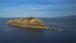 Drone shot, rocky island in calm sea under a blue sky