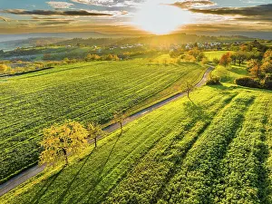 Drone view of sundown over forest and rural landscape in autumn