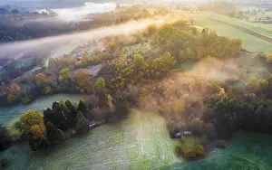 Drone view of sunrise over forest and rural landscape in autumn