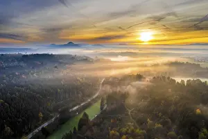Drone view of sunrise over forest and rural landscape in autumn