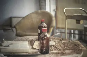 Dusty table with brown bottles and old documents in an abandoned room