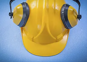 Ear muffs hard hat on blue background construction concept