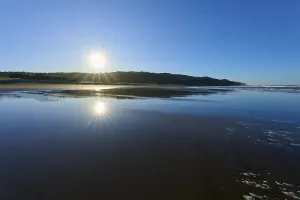 Early morning sun rays reflecting on the calm sea surface on a clear beach