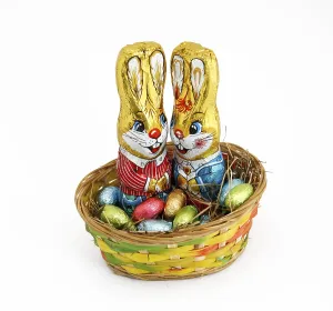 Two Easter bunnies in a basket with chocolate eggs