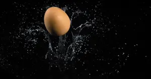 Egg Falling on Water against Black Background