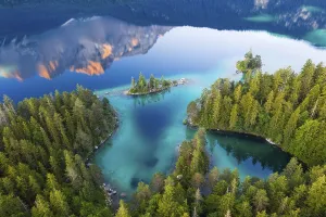 Eibsee lake with Braxen island and water reflection of the Zugspitze in the morning light