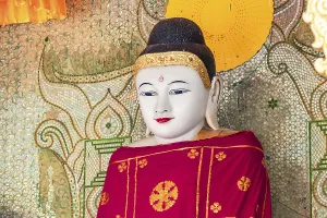Eine kunstvolle Buddha-Statue mit rotem Gewand in einem Tempel der Pollackdagon Pagode in Burmesien (Yangon)