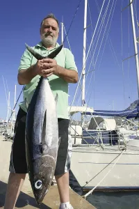 Elderly fisherman with Albacore tuna catch in hands
