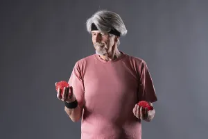 Elderly man with fitness outfit trains with fitness ball