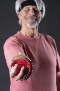 Elderly man with fitness outfit trains with fitness ball
