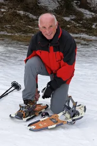 Elderly man hiking in winter with snow shoes