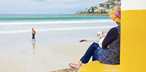 Elderly woman sitting by a beach with a dog on her lap