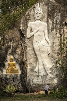 Elderly woman standing in front of a Buddha sculpture