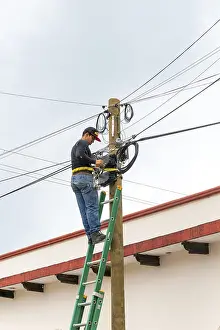 Electrician on ladder working on electricity power lines