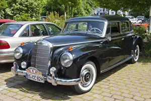 Elegant black Mercedes vintage car parked on a cobblestone car park surrounded by trees