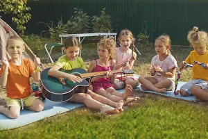The elementary school boys and girls are sitting on the grass in the backyard