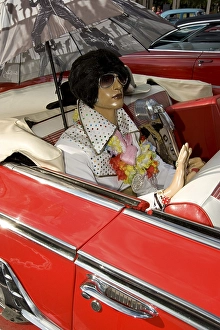 Elvis doll in the back seat of a red Cadillac Impala