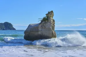 Energetic waves crash against a huge rock in the sea