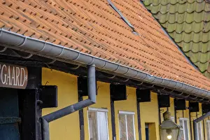 Engaged roofs and windows of a half-timbered house with yellow walls and tiles