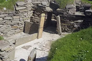 Entrance to ancient ruins with stone walls surrounded by grass and moss
