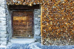 Entrance to a wine cellar framed by firewood logs