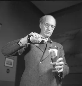Erik Olson (1886-1966) Swedish industrialist. Head of the Pripp & Lyckholm brewery in Gothenburg. He is seen pouring the content of a bottle of beer of his own companies production into a beer glass. 1943