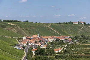 Escherndorf surrounded by hills and vineyards with a church and red roofs under a blue sky