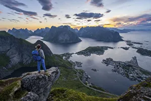 Evening atmosphere, young hiker standing on a rocky outcrop and enjoying the view from Reinebringen