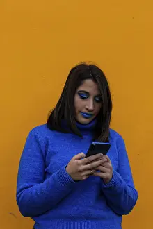 Excited young lady with blue clothes chatting with her mobile