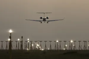 Executive business jet passenger aircraft landing over runway lights at sunset